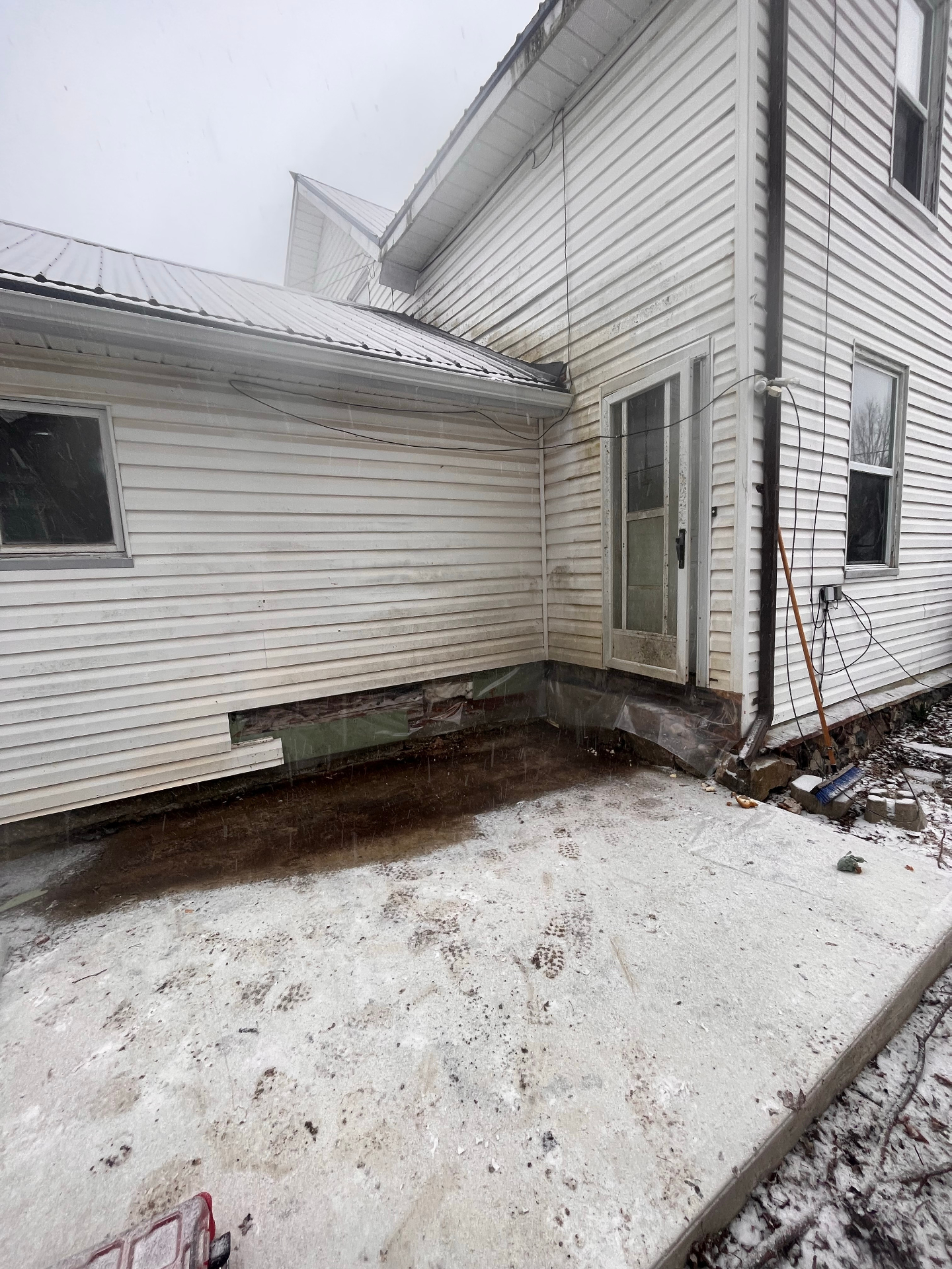 Before photo of weathered white siding and entry area during winter conditions