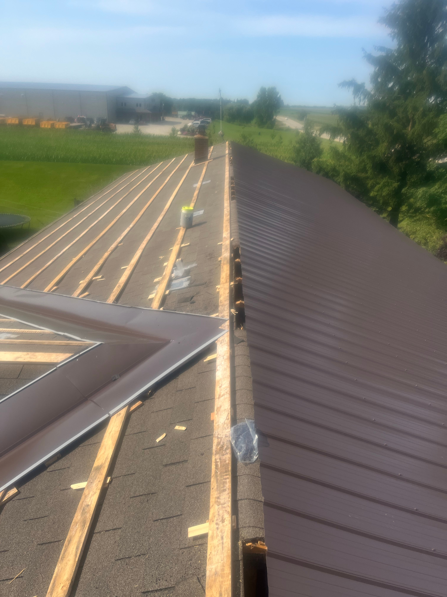 Brown metal roofing installation in progress with strapping visible on half the roof