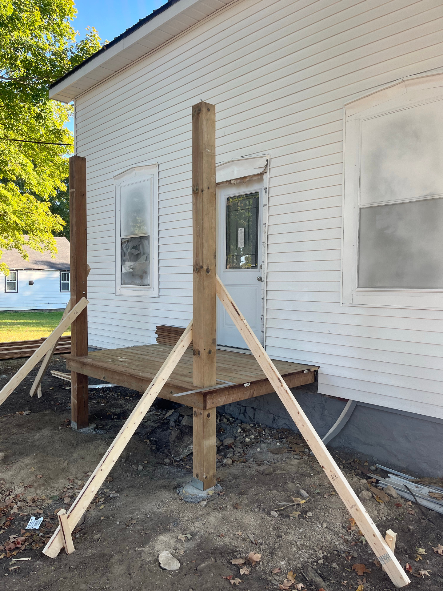 New front porch framing and deck build in progress on a white farmhouse