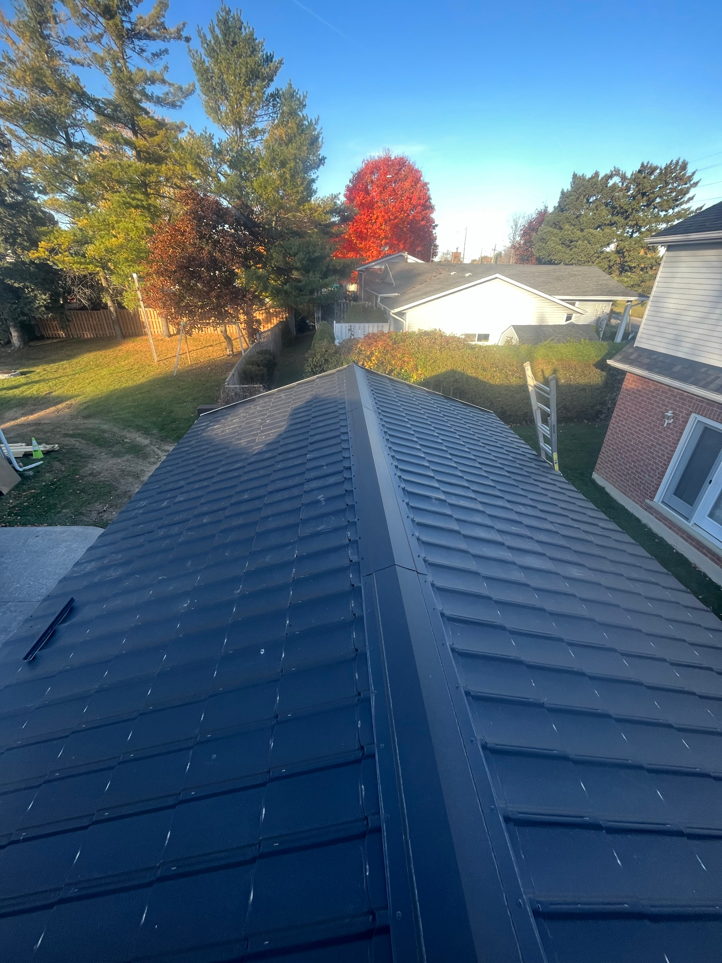 Completed dark metal roof with stone-coated profile on a residential addition