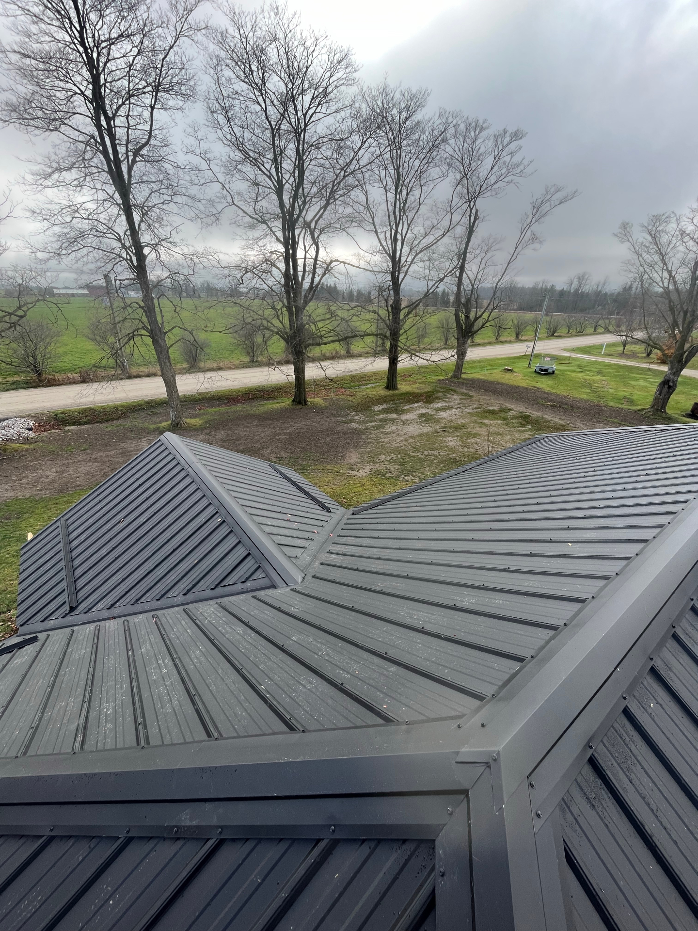 Finished charcoal metal roof with clean valleys and ridge details on a rural property
