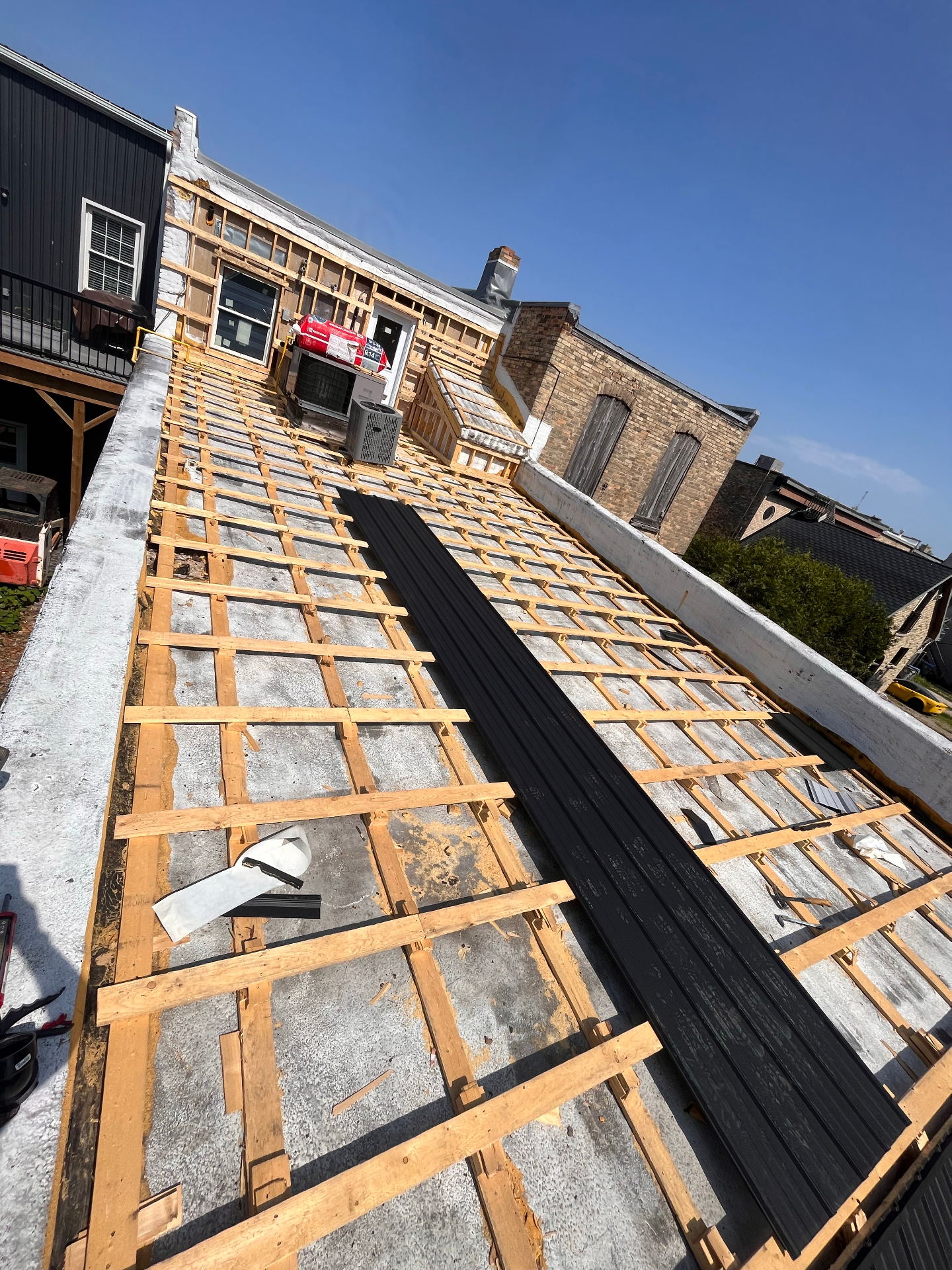 Strapping installed and metal roofing panels staged on a downtown commercial roof