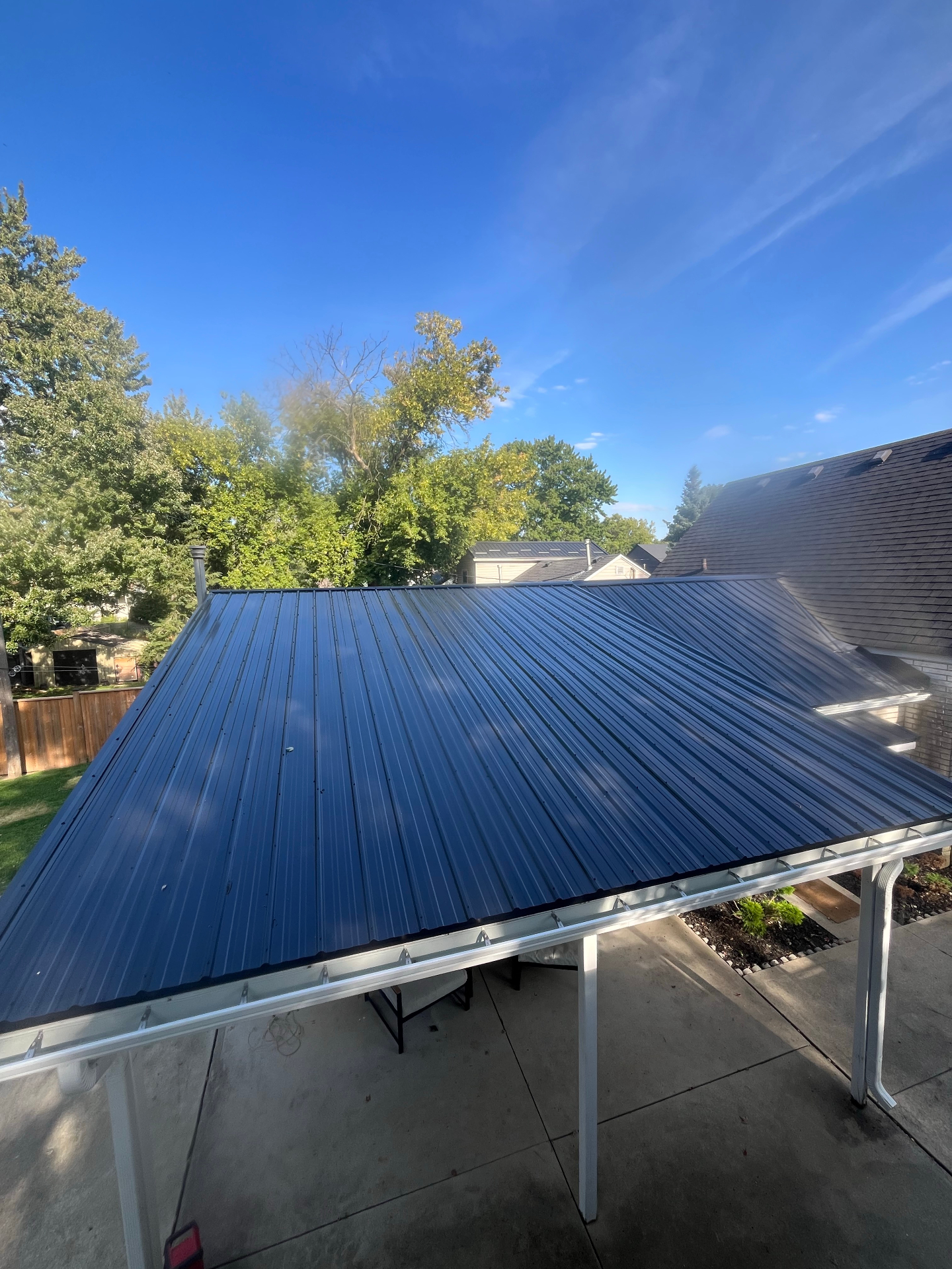 New black metal roof installed on a backyard patio cover with fresh aluminum gutters