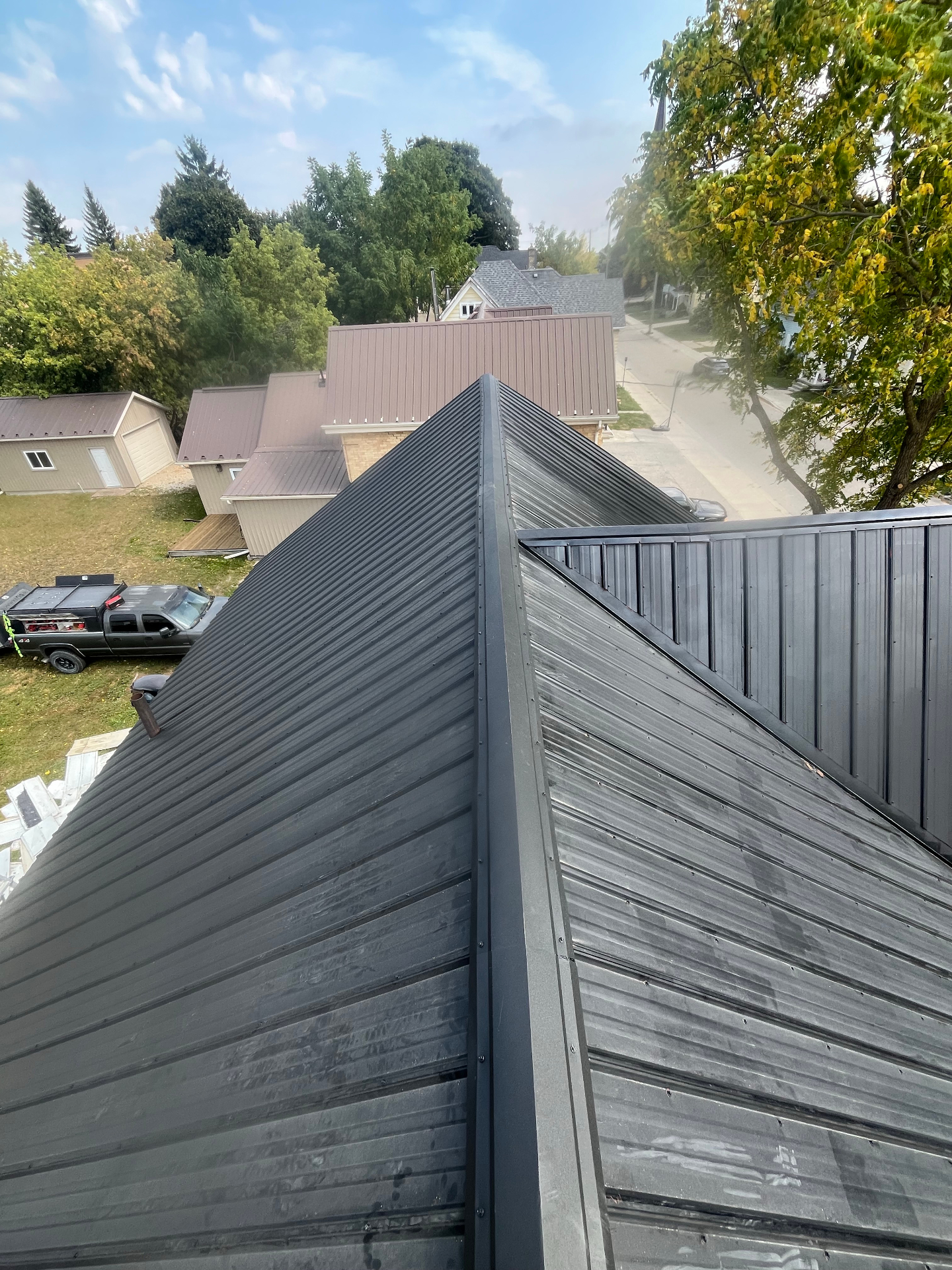 Freshly installed charcoal metal roof with crisp hip ridges on a residential home in town