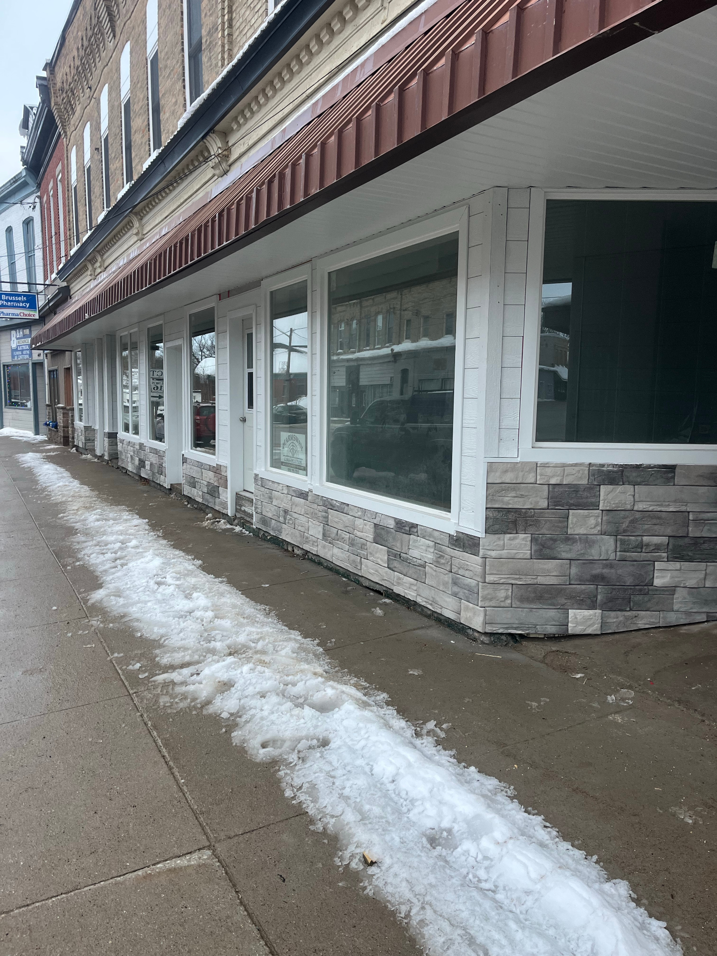 Completed downtown Brussels storefront renovation with new white trim, stone veneer, and brown metal awning