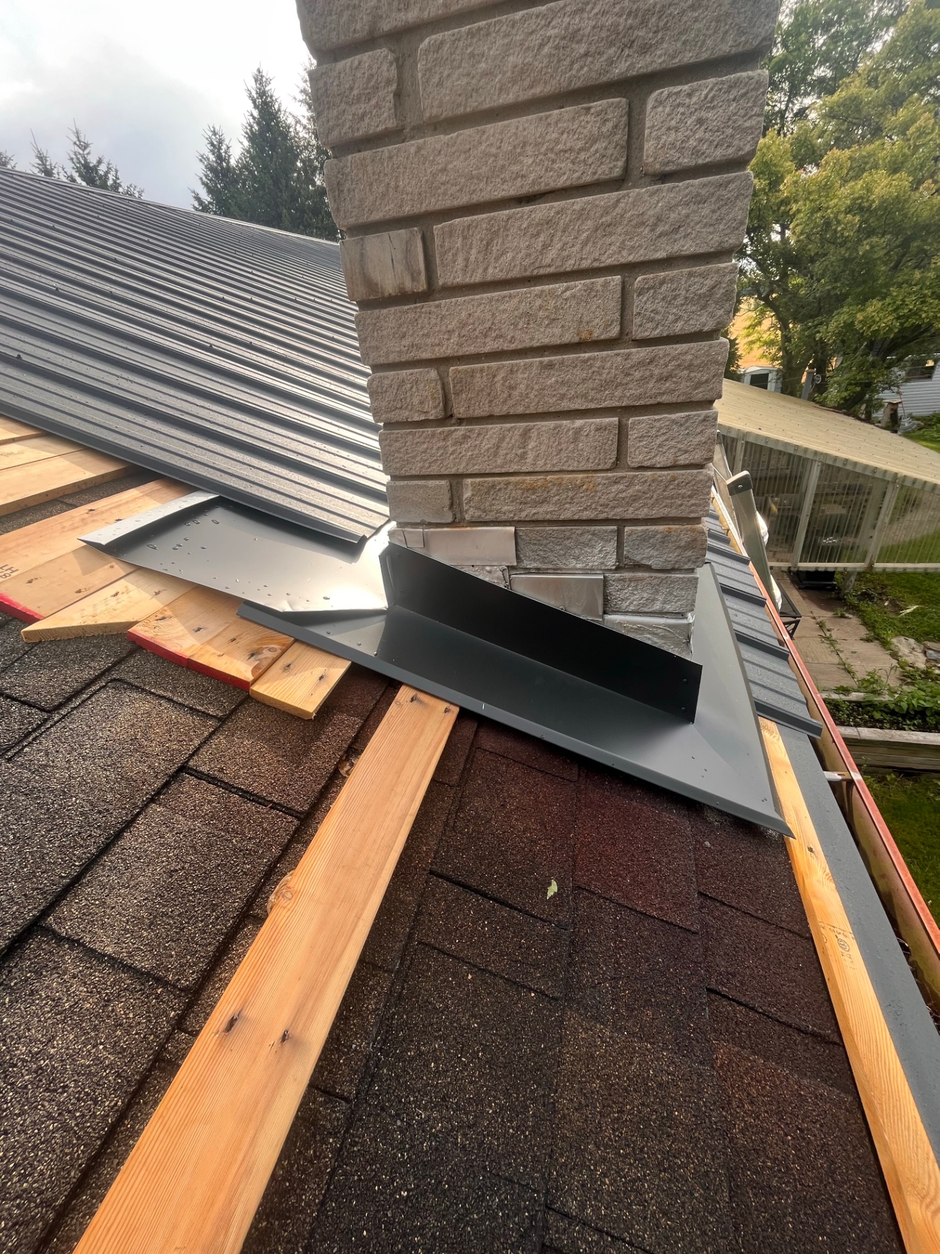Custom-bent chimney flashing and metal roof transition over an existing brick chimney