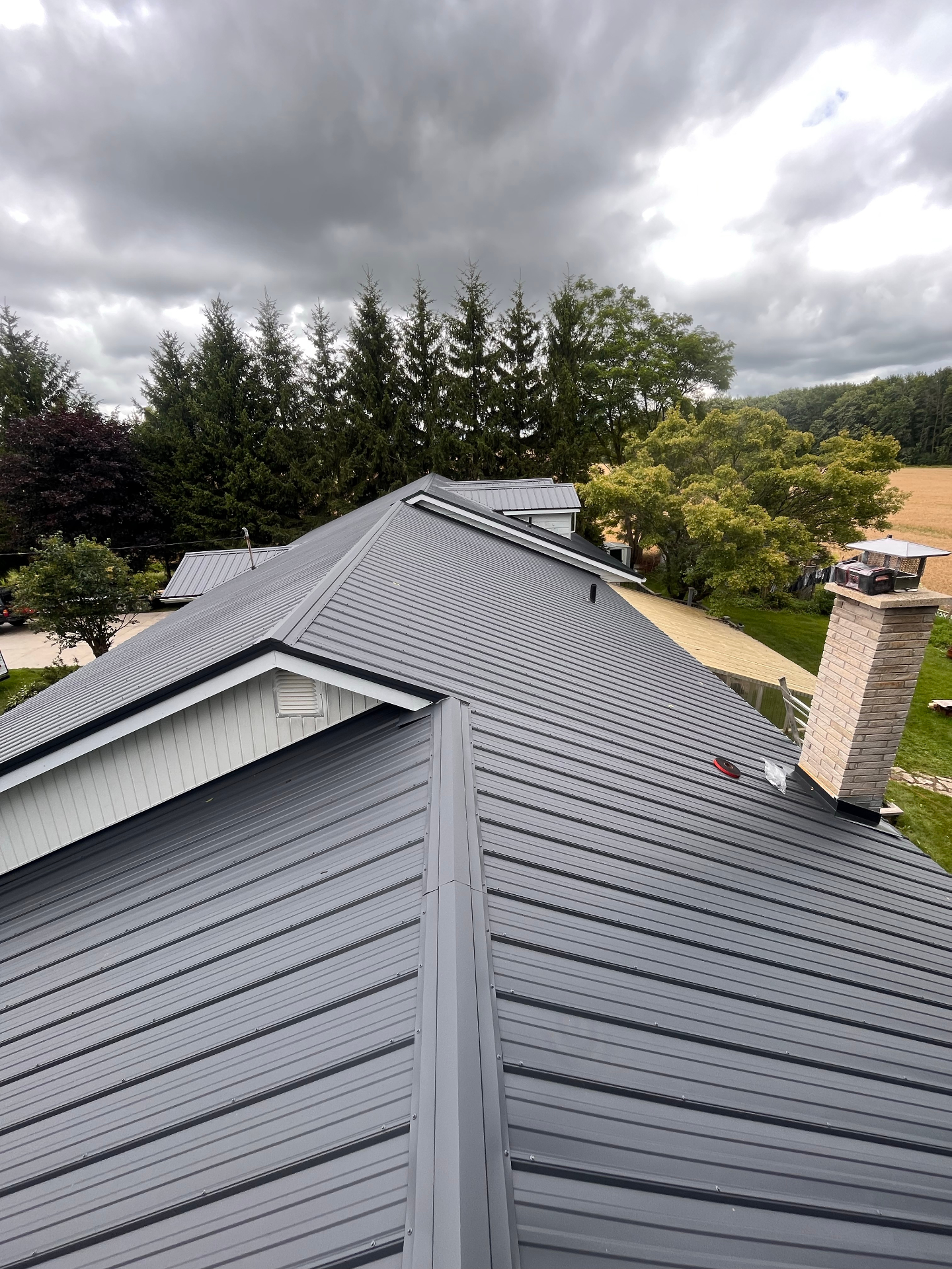 Completed metal roof with crisp ridge caps and hip details on a Brussels-area home